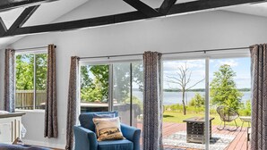 A room with a large sliding glass door leading to an outdoor deck with a view of a lake. - Table Rock Lakefront Studio w Access_Private Hot Tub_Free Daily Tickets (Hollister)