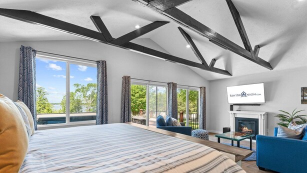 A modern bedroom with a large bed, a TV, and a fireplace. - Table Rock Lakefront Studio w Access_Private Hot Tub_Free Daily Tickets (Hollister)