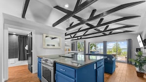 A modern kitchen with blue cabinets, a large island, and exposed ceiling beams. - Table Rock Lakefront Studio w Access_Private Hot Tub_Free Daily Tickets (Hollister)