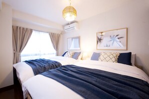 Una habitació d'hotel amb un llit gran, dues taules de nit, aire condicionat fixat a la paret i una làmpada al sostre.