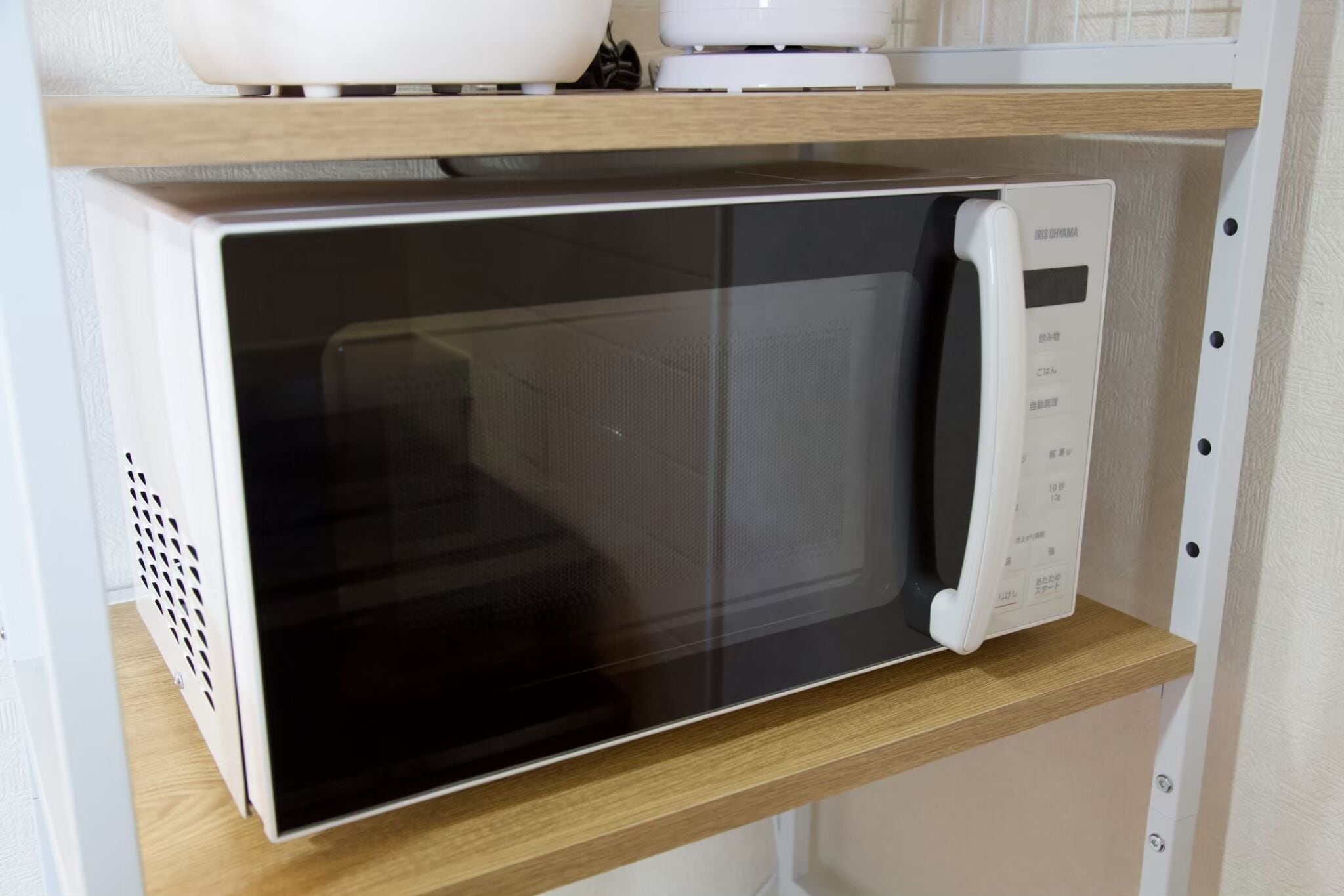 Un horno microondas sobre una repisa de madera.