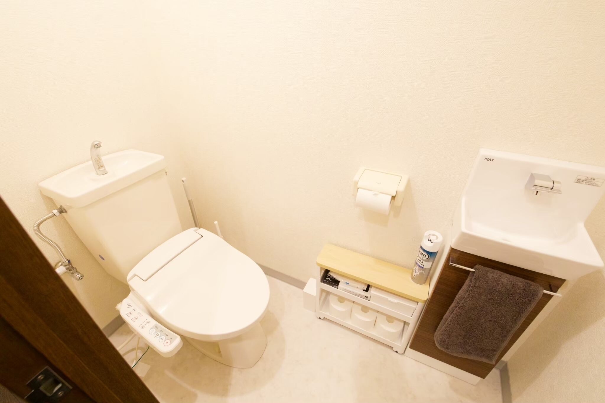 A small bathroom with a toilet, a sink, a towel rack, and a toilet paper holder.