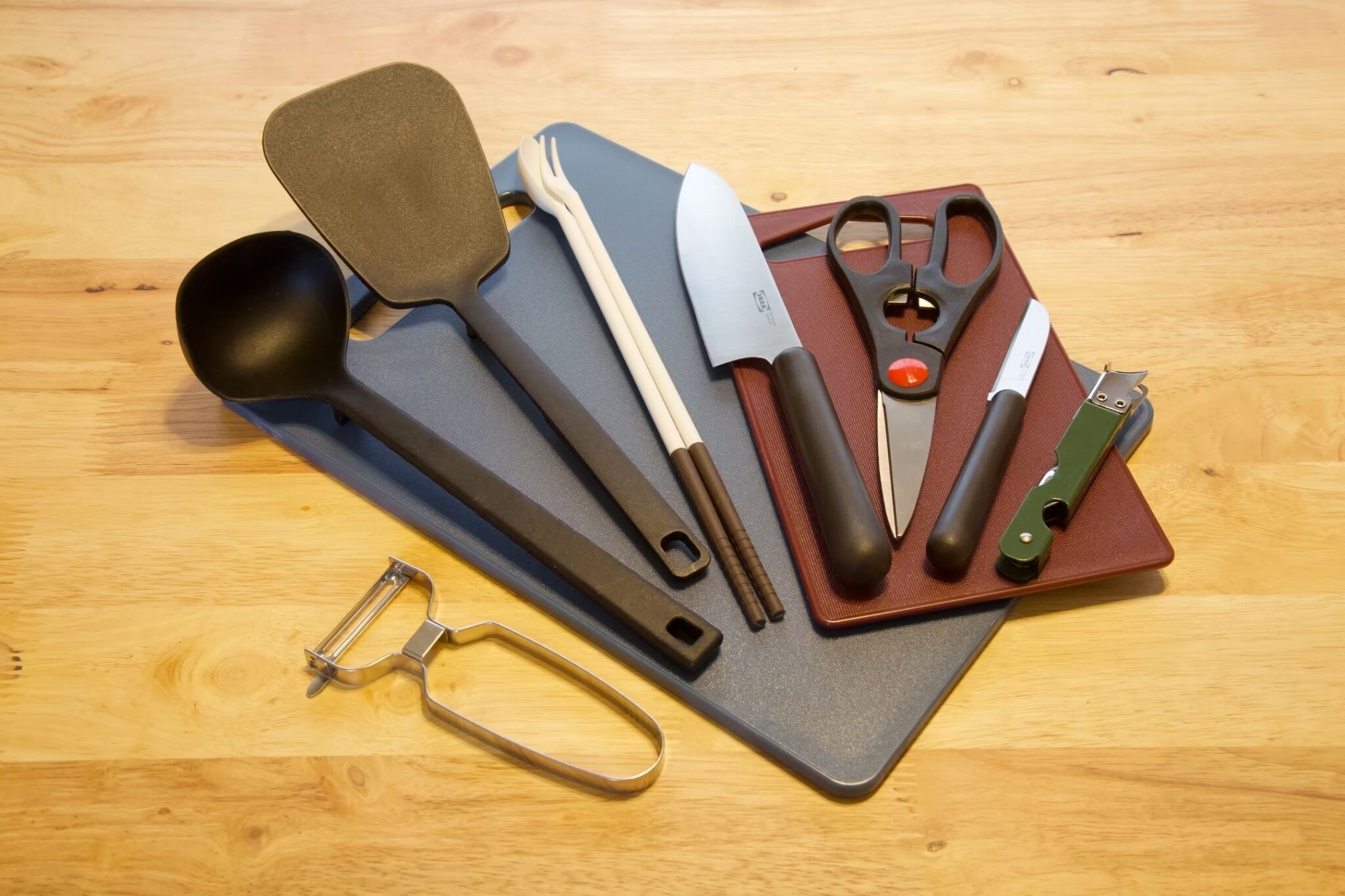 A collection of kitchen utensils and tools arranged on a wooden surface.