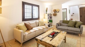 Ein Wohnzimmer mit zwei Sofas, einem Couchtisch, einem Bücherregal und einem Fenster mit Gitterstäben.