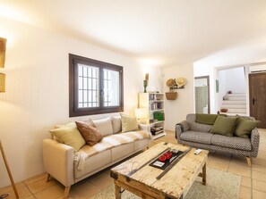 A living room with two sofas, a coffee table, a bookshelf, and a window with bars. - Rustic house with a swimming pool in Nigüelas (Nigüelas)