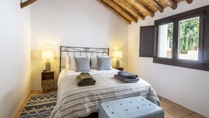 Ein Schlafzimmer mit einem Bett, zwei Nachttischen, einem Fenster und einer rustikalen Decke.