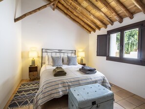 A bedroom with a bed, two bedside tables, a window, and a rustic ceiling. - Rustic house with a swimming pool in Nigüelas (Nigüelas)