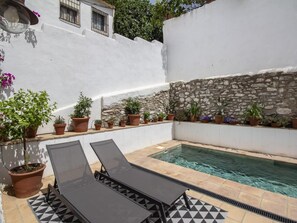 A pool area with lounge chairs, potted plants, and a stone wall. - Rustic house with a swimming pool in Nigüelas (Nigüelas)