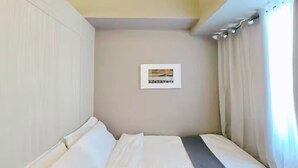 A small, single-bed room with a plain wall and a framed picture. - Citispace1BRSuite at SM Light Residences (MANDALUYONG)