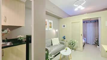 A modern interior with a kitchenette, a grey sofa, and a small white table.