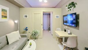 A modern living room with a sofa, coffee table, and a TV mounted on the wall. - Citispace1BRSuite at SM Light Residences (MANDALUYONG)