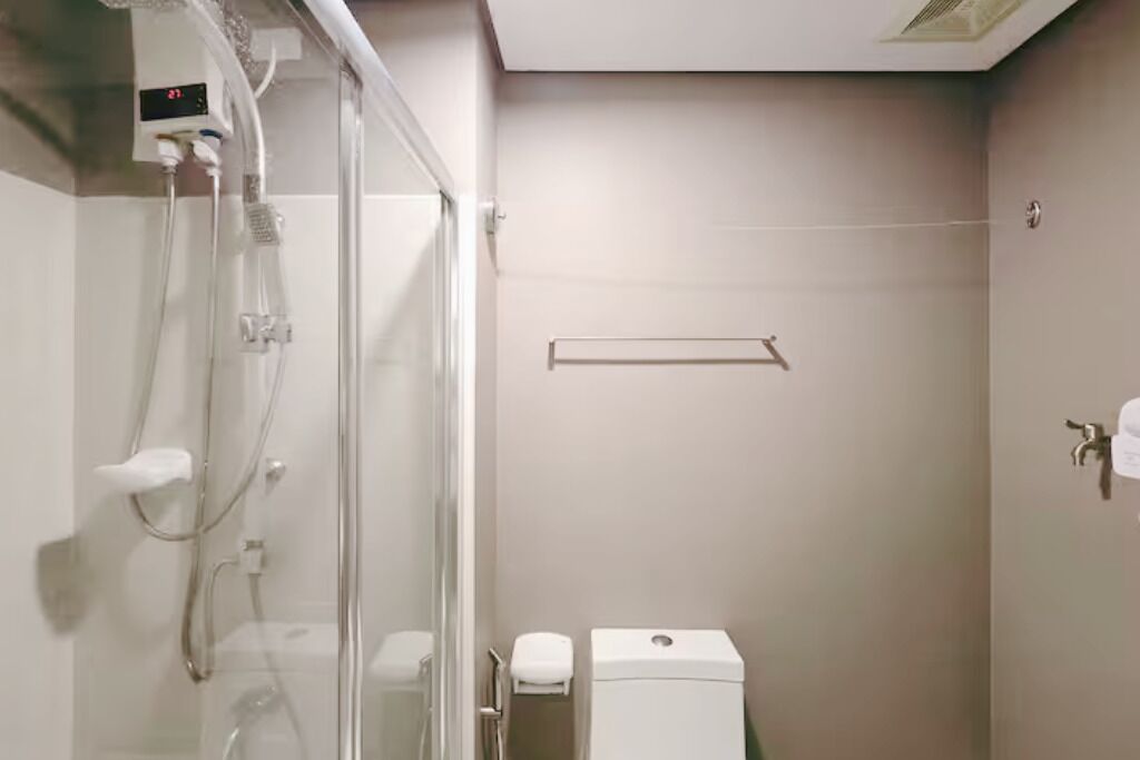 Un baño con cabina de ducha de vidrio, un inodoro y un perchero para toallas.
