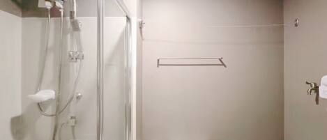 Un baño con cabina de ducha de vidrio, un inodoro y un perchero para toallas.