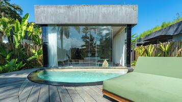 Uma área de piscina moderna ao ar livre, com cobertura de vidro, deck de madeira e sofá verde.