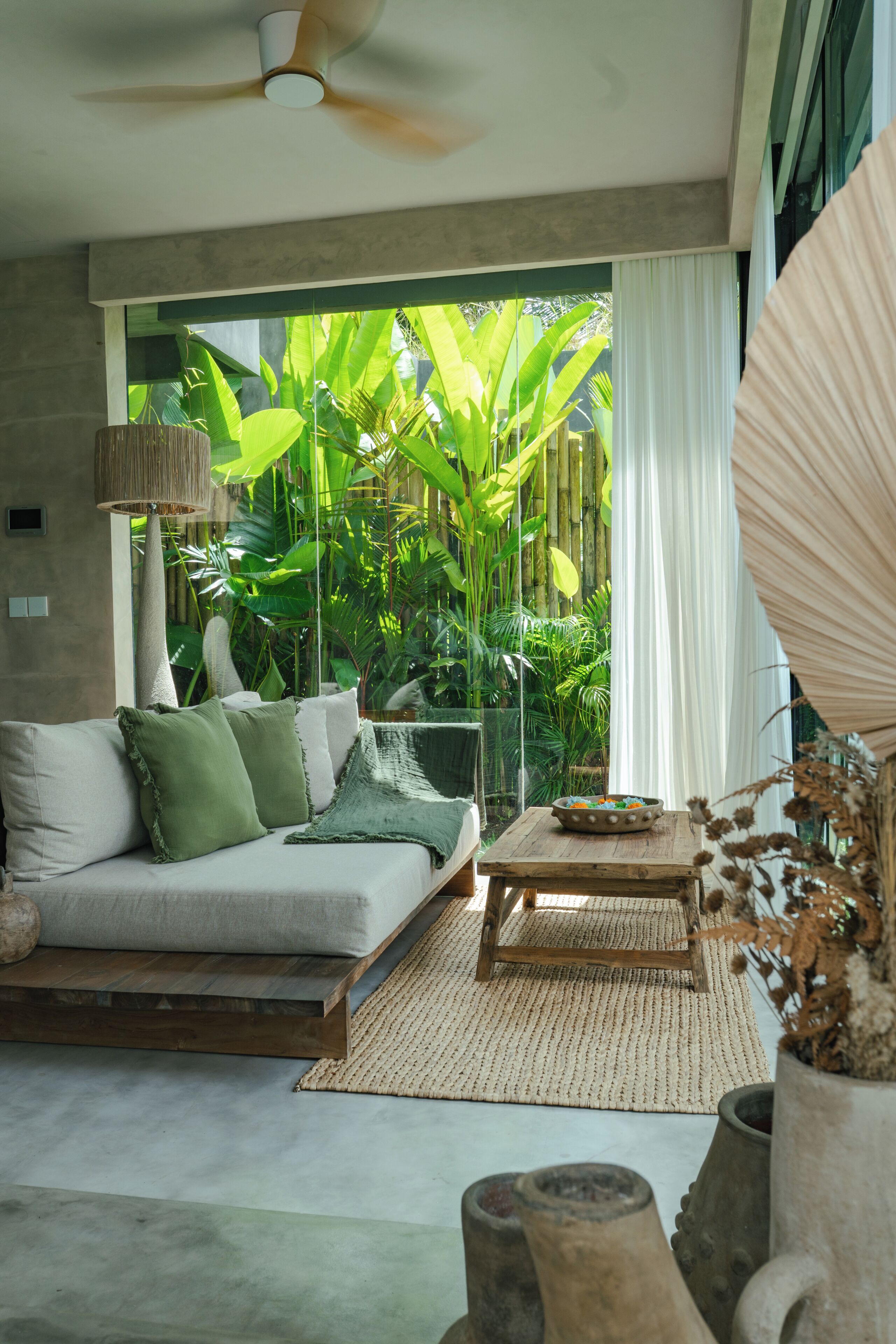 Sala moderna com sofá, mesa de centro e vista para um verde exuberante.