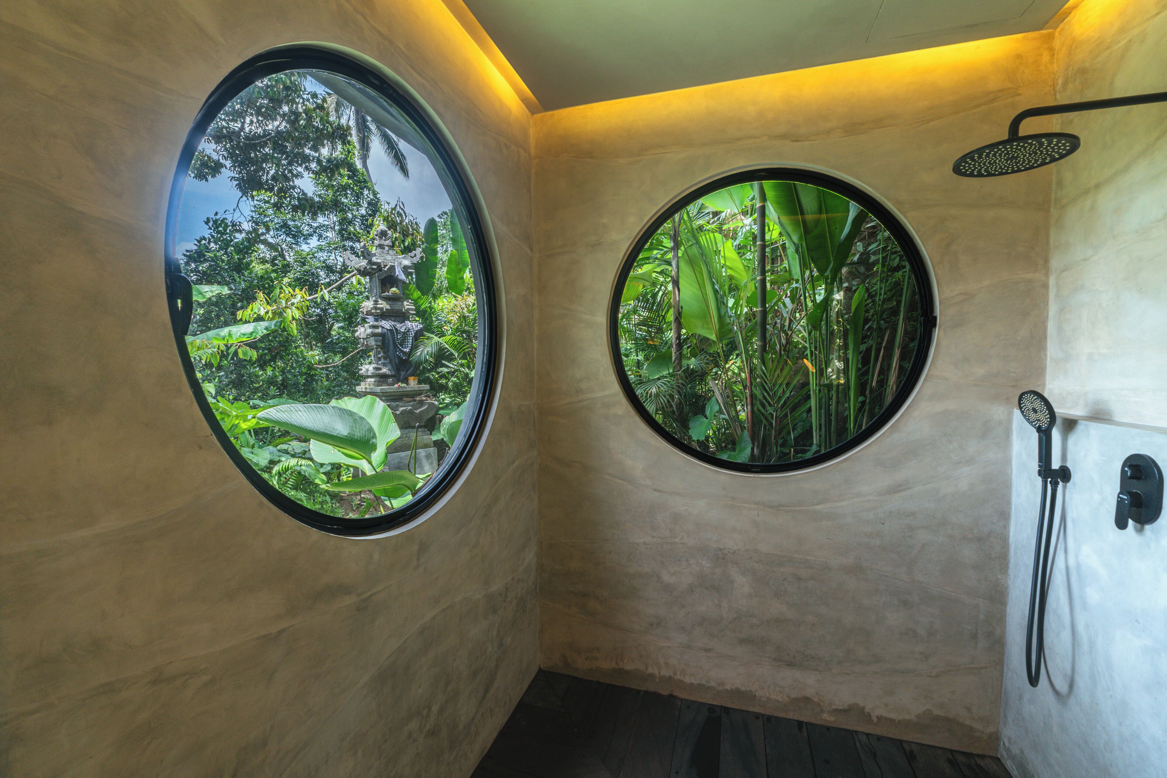 Une salle de bain avec deux fenêtres rondes, une douche et une vue sur un jardin.