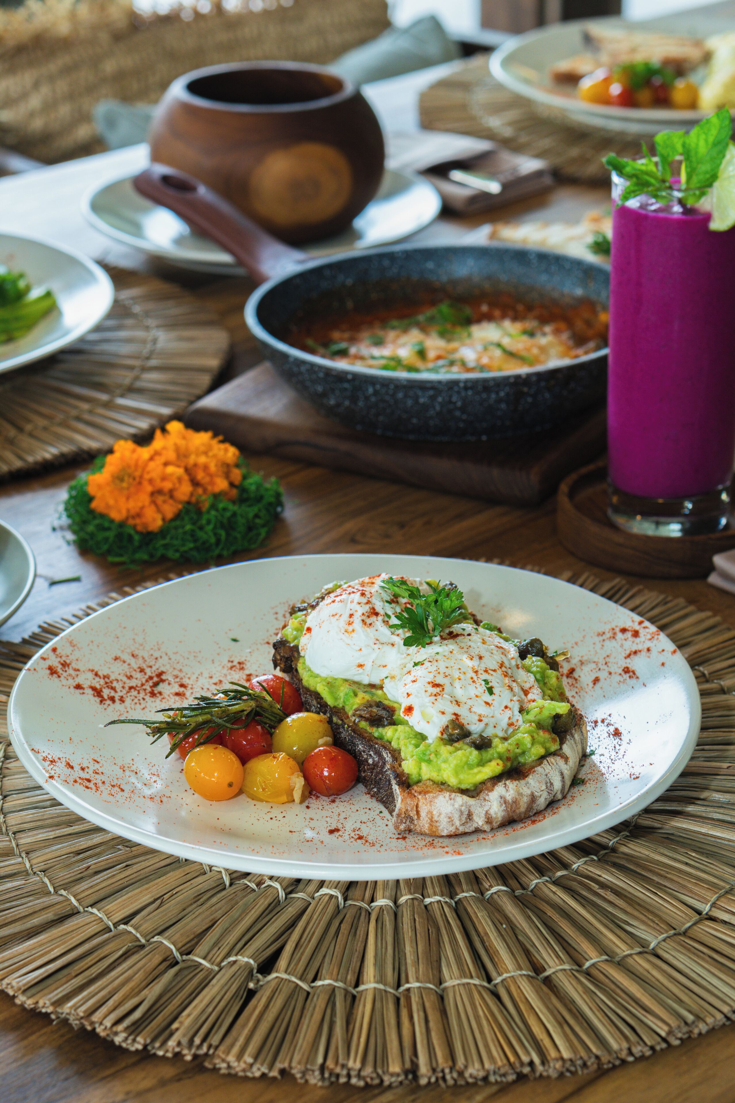A plate of food with a poached egg, avocado, and vegetables on a woven placemat.