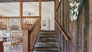 Eine Treppe mit Holzgeländern führt zu einem Raum mit einem Esstisch und Stühlen.