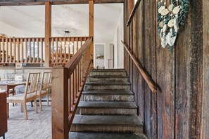 Eine Treppe mit Holzgeländern führt zu einem Raum mit einem Esstisch und Stühlen.