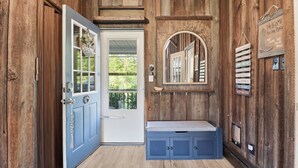 Ein Holzinterieur mit einer blauen Tür, einem Willkommensschild, einem Spiegel und einem Regal mit motivierenden Schildern.