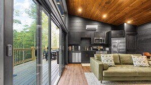 A modern kitchen with dark cabinetry, stainless steel appliances, and a wooden ceiling. - Couples Retreat–2 Private Cabins,Hot Tubs,Firepits (Sevierville)