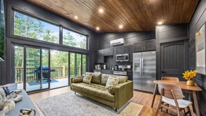 A modern kitchen with dark cabinetry, a built-in microwave, and a refrigerator. - Couples Retreat–2 Private Cabins,Hot Tubs,Firepits (Sevierville)