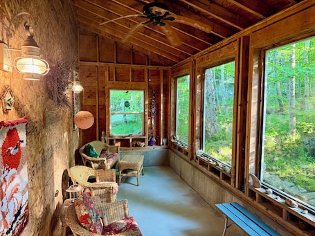 A cozy cabin with wicker furniture, a large window, and a wooden ceiling.. Escape the Crowds at MDI’s Historic Birthplace