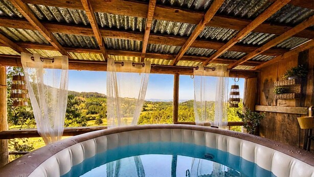 A hot tub with a view of a green landscape.