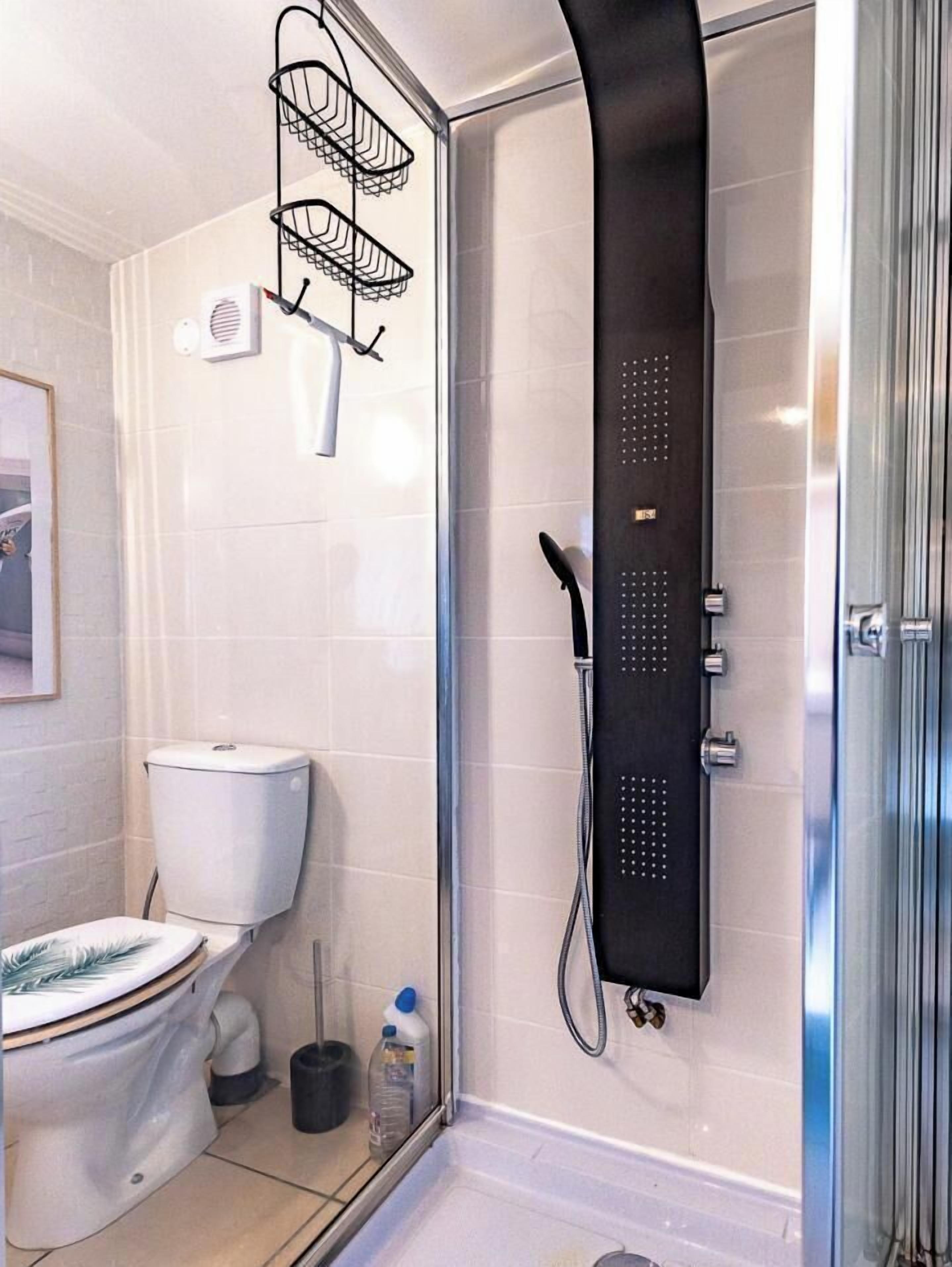 Une salle de bain moderne avec une douche à parois de verre, des toilettes, un lavabo et un porte-serviettes.