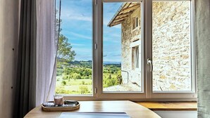 A room with a large window, a wooden table, and a remote control.