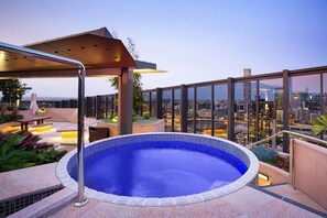 Ein Pool auf dem Dach mit Blick auf die Stadt, einer überdachten Sitzgelegenheit und einer Glasuhrung.
