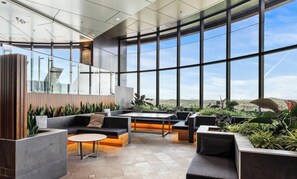 Ein modernes Interieur mit großen Fenstern, einer Sitzecke mit Sofas und einem Tisch sowie Blick auf die Stadt.