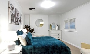 Ein Schlafzimmer mit Bett, Schminktisch, Spiegel und Wandbildern.