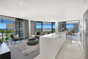 A modern apartment with a living area, kitchen, and large windows offering city views. - Coastal Vibe at Oracle Level 10 (Gold Coast)