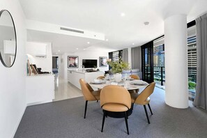 A modern kitchen with a dining area, a large mirror, and a view of the city. - Coastal Vibe at Oracle Level 10 (Gold Coast)