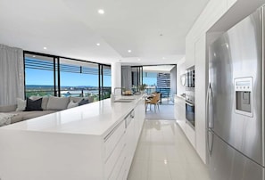 A modern kitchen with a large island, stainless steel appliances, and a view of the city. - Coastal Vibe at Oracle Level 10 (Gold Coast)
