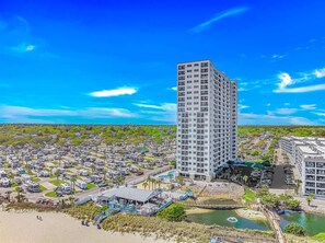 A tall hotel with multiple floors, a parking lot, and a beach area. - Ocean View 2BR Retreat-Renaissance Tower 1616 (Myrtle Beach)