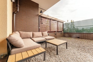 Eine Terrasse mit einer Couch, einem Holztisch und einer Backsteinmauer.