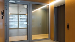 Elevador moderno com acabamento em madeira e painel digital.