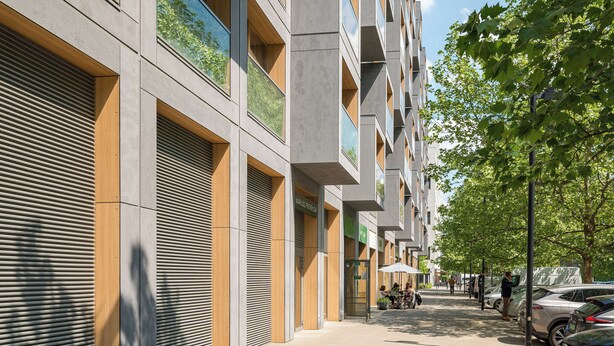 Um edifício moderno com persianas fechadas, uma fileira de varandas e uma rua arborizada.