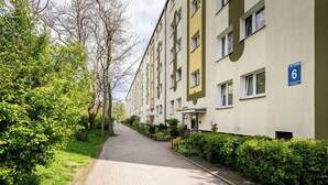 Edifício residencial com caminho pavimentado, áreas verdes e uma placa indicando o número 6.