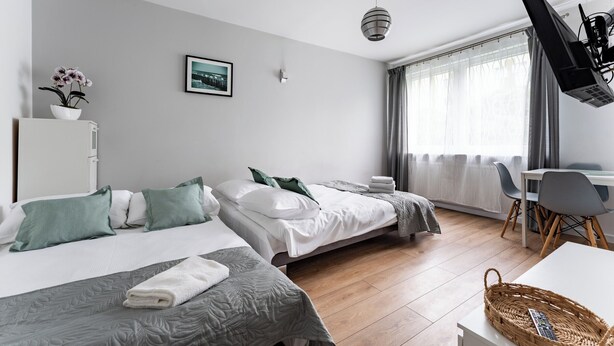 Quarto de hotel com duas camas, uma escrivaninha, uma cadeira, uma televisão e uma janela com cortinas.