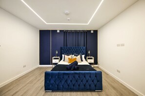 A bedroom with a large bed, two bedside tables, a headboard, and a ceiling light fixture. - Islington Garden Studio, Sleeps 4, Pet-Friendly! (Greater London)