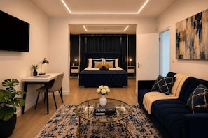 A modern bedroom with a bed, bedside tables, a desk, a sofa, and a TV. - Bright N1 Studio | Tube + Garden | Sleeps 4 (Greater London)