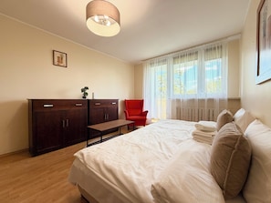 Ein Schlafzimmer mit Bett, Schreibtisch, Stuhl und einem Fenster mit Vorhängen.