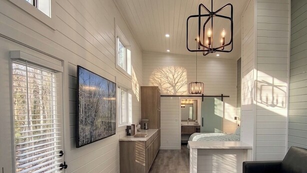 A spacious room with a large bed, a seating area, and a view of the outdoors. - Camp Cottonwood  (Cottonwood)