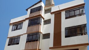 Un edificio de varios pisos con balcones, ventanas amplias y techo plano.