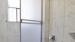 Un baño con inodoro, ducha y ventana.