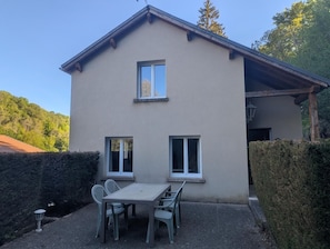 Ein zweistöckiges Haus mit einer Terrasse, komplett mit Tisch und Stühlen.
