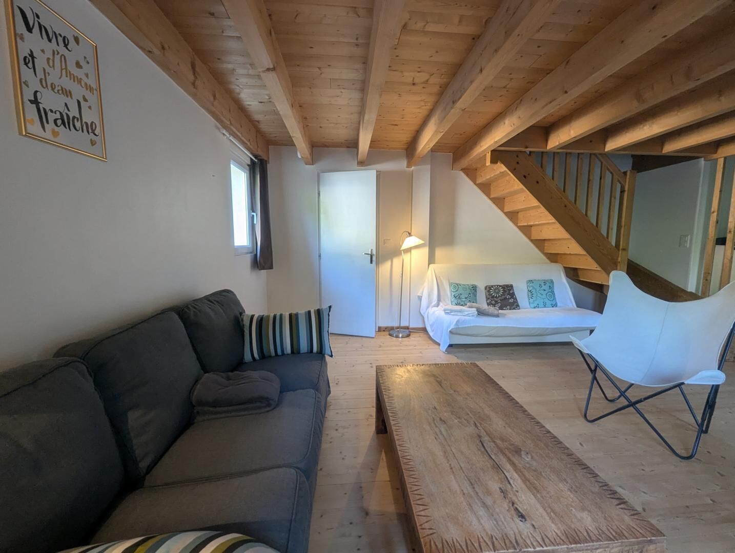 A cozy living room with a sofa, a wooden coffee table, a white couch, and a staircase.